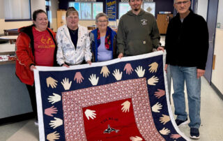 group of people holding a quilt