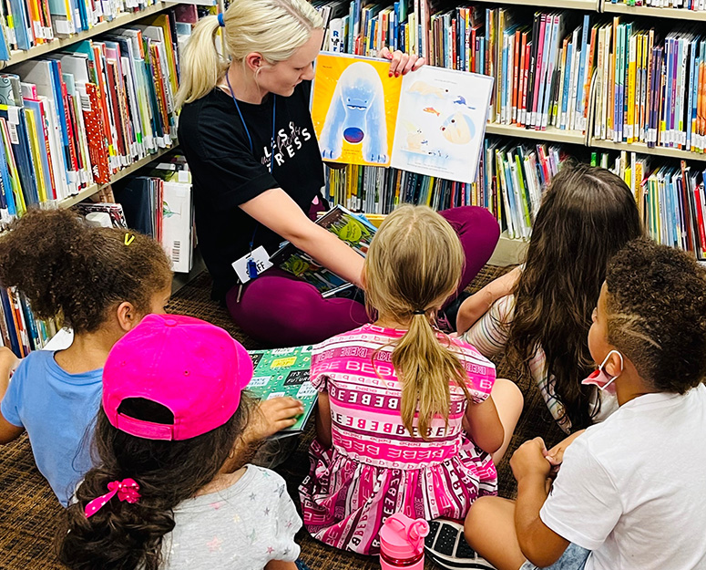 mukilteo_childcare Mukilteo woman reading storybook to kids seated on flor