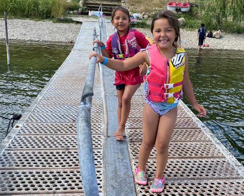 Nespelem 2 girls in swimsuits and life jackets walking on a