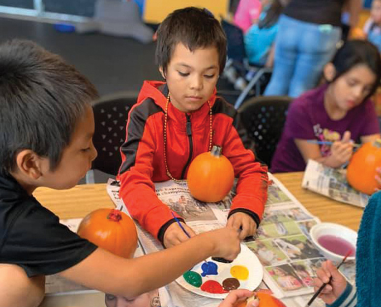 Nespelem boys decorating small pumpkins with paint