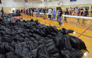large pile of backpacks in gym