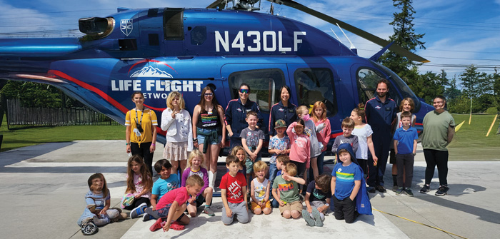 group of kids and adults standing in front of helicopter