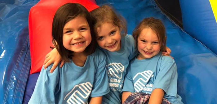 3 smiling girls wearing boys and girls club t-shirts