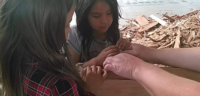 close up of 2 girls looking at seashell on beach
