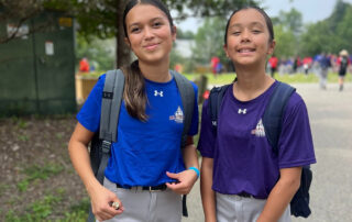 2 girls in baseball gear with backpacks