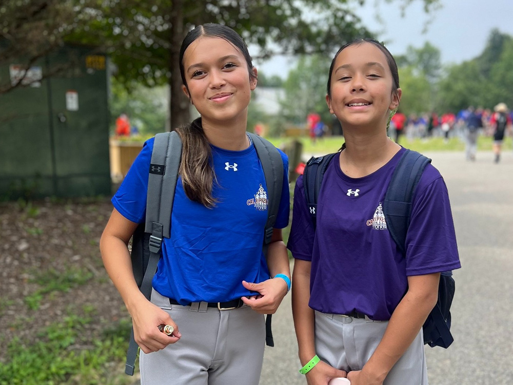 2 girls in baseball gear with backpacks