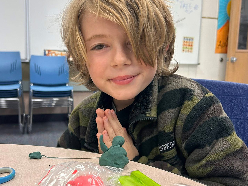 child sitting at table with hands pressed together