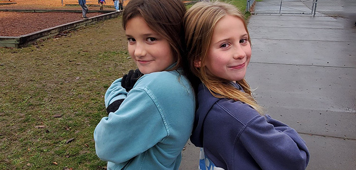 2 girls standing back to back with arms crossed