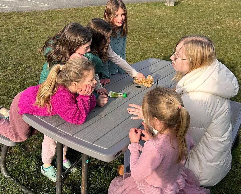 summer_camp_SWhidbey Adult and 4 kids sitting outside at a picnic table