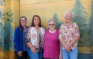 4 women standing in front of a mural