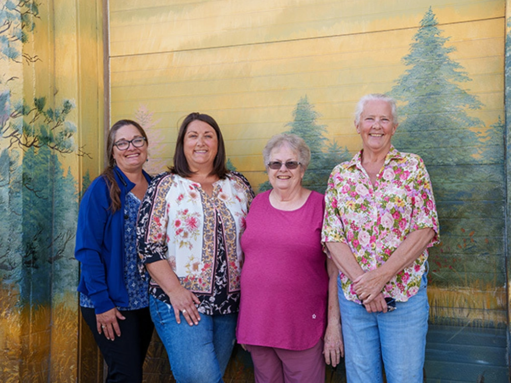 4 women standing in front of a mural