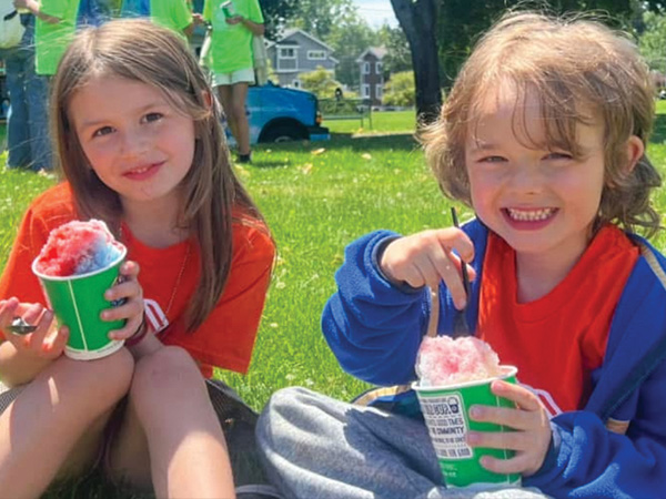 Two girls sitting on grass eating ices
