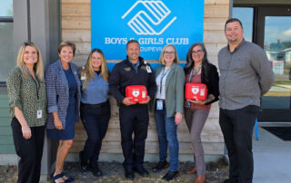 people standing in front of Boys & Girls Club holding AED kits