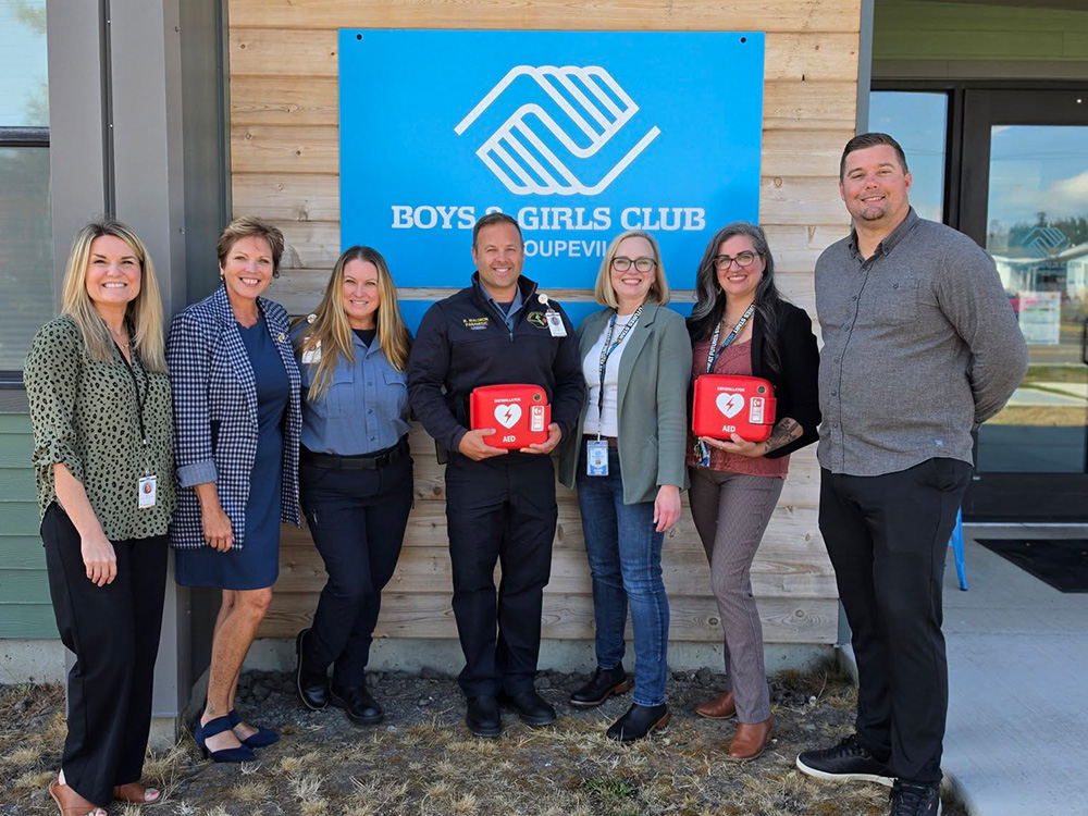 people standing in front of Boys & Girls Club holding AED kits